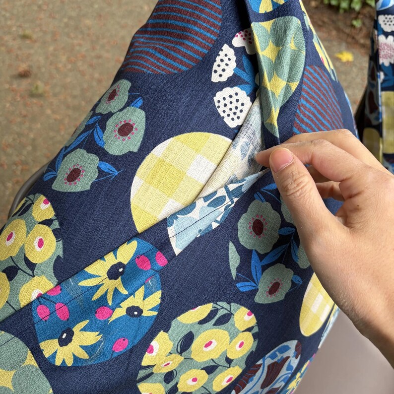 May include: A dark blue fabric cushion cover featuring a repeating pattern of large circles. The circles contain various designs including yellow flowers, light green floral motifs, yellow and white gingham checks, and dark red diagonal stripes.