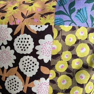 Peut inclure: Un tissu patchwork compos&eacute; de quatre motifs floraux distincts. Une section pr&eacute;sente des fleurs jaunes sur fond beige, une autre des fleurs bleues sur lavande, une troisi&egrave;me des fleurs blanches sur brun fonc&eacute; et la quatri&egrave;me des cercles jaunes sur olive.
