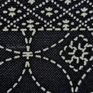 May include: A black fabric featuring a white stitched geometric pattern with repeating diamond and floral-like shapes. The embroidery consists of small, dashed lines creating a textured surface. The text Sozar Studio is visible in white.