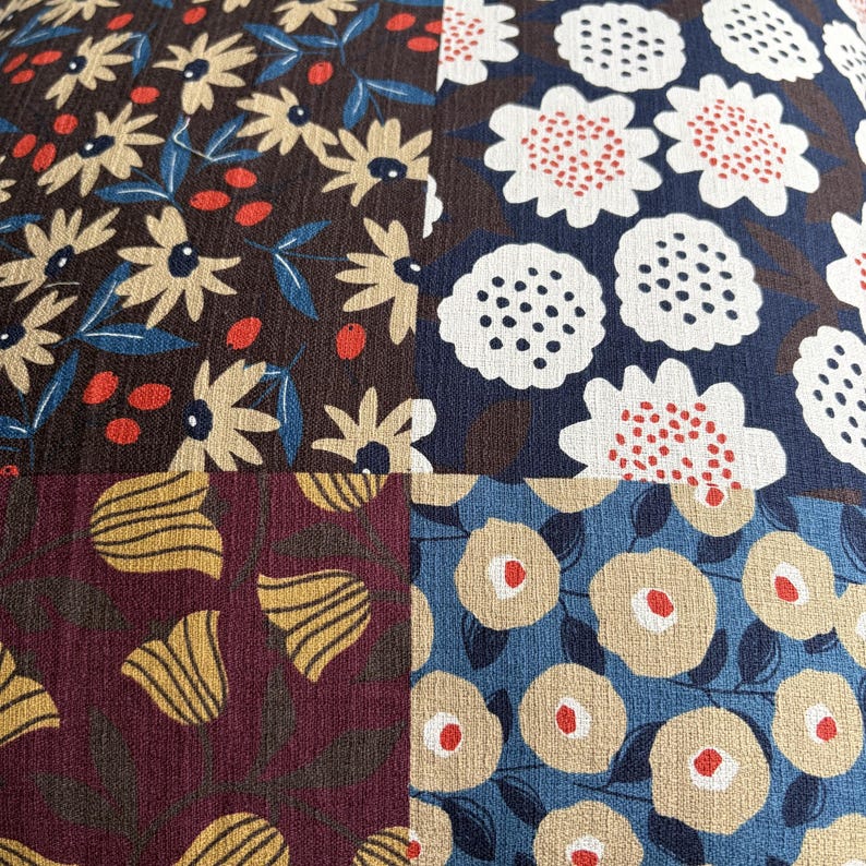 May include: A square textile panel featuring a patchwork design of four distinct floral patterns. The top left shows cream flowers on brown, top right white flowers on navy, bottom left yellow tulips on maroon, and bottom right beige flowers on blue.