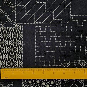 May include: A dark navy blue fabric featuring a white geometric sashiko-style stitched pattern with various repeating motifs including floral waves, squares, and dots. A yellow ruler is placed at the bottom, showing a length of 8 inches.