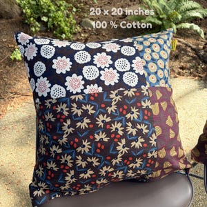 May include: A square 20 x 20 inches 100% cotton throw pillow featuring a patchwork design of various floral patterns. The fabric sections display white and red flowers on navy, beige flowers on blue, and yellow tulips on a deep maroon background.
