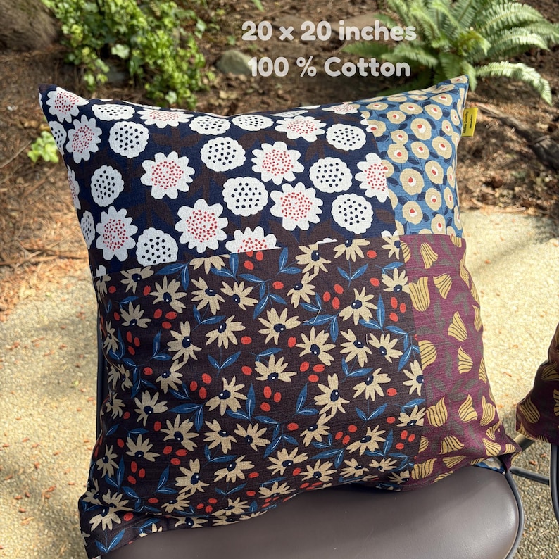 May include: A square 20 x 20 inches 100% cotton throw pillow featuring a patchwork design of various floral patterns. The fabric sections display white and red flowers on navy, beige flowers on blue, and yellow tulips on a deep maroon background.