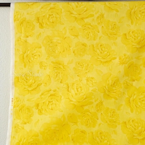 May include: Bright yellow fabric with a repeating pattern of large, detailed rose blooms. The roses are in various stages of bloom, creating a textured and visually rich design. The fabric is suitable for sewing projects.