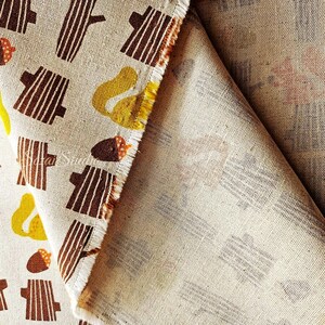 Pu&ograve; includere: Tessuto beige con un motivo ripetuto di tronchi d'albero marroni, pere gialle e ghiande marroni. Il tessuto &egrave; piegato, rivelando il rovescio con una versione sbiadita dello stesso motivo. I bordi sono sfilacciati.