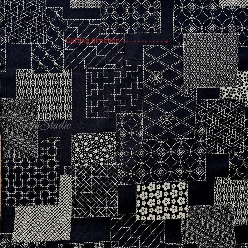 May include: A dark navy blue fabric featuring a patchwork design of various white geometric and floral patterns. The textile includes a red arrow with the text Cutting direction and the word SenseiStudio printed in white script on the left side.