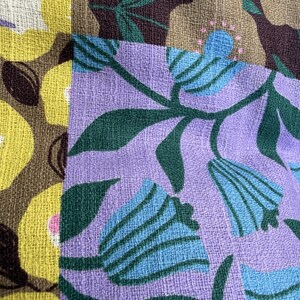Peut inclure: Un tissu textile pr&eacute;sentant un motif en patchwork avec deux imprim&eacute;s floraux distincts. Une section affiche des fleurs jaunes sur fond marron, tandis que l'autre montre des fleurs bleues en forme de cloche sur fond lavande avec des feuilles vert fonc&eacute;.