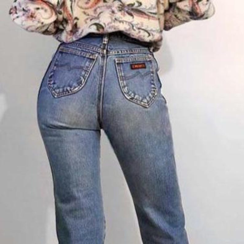 Puede incluir: Vaqueros de mezclilla azul claro con cintura alta y dise&ntilde;o cl&aacute;sico de cinco bolsillos. Los vaqueros tienen un corte de pierna recta y un peque&ntilde;o parche con el logo naranja en el bolsillo trasero. La modelo lleva un su&eacute;ter estampado.