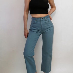 May include: A person wearing a black mock neck shirt and blue jeans with a raw hem.
