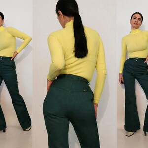 Puede incluir: Una mujer lleva un jersey de cuello alto amarillo y pantalones acampanados verde oscuro. Los pantalones tienen cintura alta y pierna ancha.