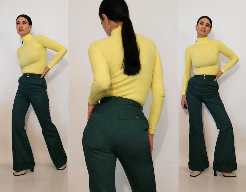 Puede incluir: Una mujer lleva un jersey de cuello alto amarillo y pantalones acampanados verde oscuro. Los pantalones tienen cintura alta y pierna ancha.