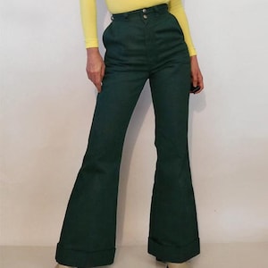 Puede incluir: Un pantal&oacute;n de campana verde oscuro con cintura alta y cierre de bot&oacute;n. El pantal&oacute;n tiene una abertura de pierna ancha y est&aacute; hecho de una tela suave.