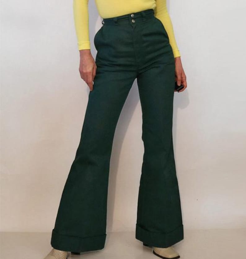 Puede incluir: Un pantal&oacute;n de campana verde oscuro con cintura alta y cierre de bot&oacute;n. El pantal&oacute;n tiene una abertura de pierna ancha y est&aacute; hecho de una tela suave.