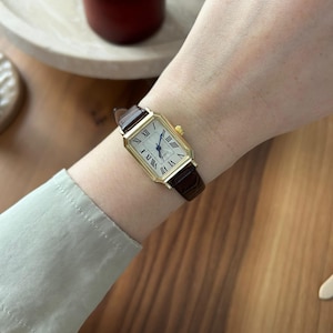 Rektangulär guldfärgad damklocka, mörkbrunt läderarmband, tankklocka i vintagestil, romerska siffror, blå visare, klassisk present till damer