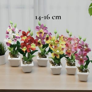 Peut inclure: Six orchidées artificielles colorées dans des pots carrés blancs. Les fleurs sont dans des tons de rose, jaune, rouge et violet. Chaque plante mesure environ 14 à 16 cm de haut. Le texte "14-16 cm" est visible.