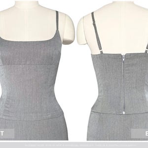 Puede incluir: Un conjunto gris de dos piezas exhibido en un maniqu&iacute;. La parte superior es una camiseta sin mangas ajustada con tirantes finos y un escote cuadrado. La vista trasera muestra un cierre de cremallera. La parte inferior es una falda a juego.
