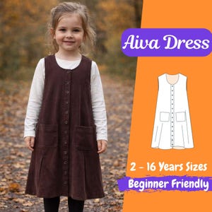 Può includere: Una bambina indossa un abito Aiva in velluto a coste marrone sopra una camicia bianca a maniche lunghe. L'abito ha una chiusura con bottoni e due tasche frontali. L'immagine include il testo "Aiva Dress", "2 - 16 Years Sizes" e "Beginner Friendly".