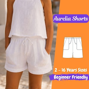 May include: A white shorts and top set. The shorts feature pockets and a drawstring. The image includes a diagram of the shorts and text: "Aurelia Shorts", "2 - 16 Years Sizes", and "Beginner Friendly".