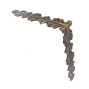 May include: A brass corner bracket with a decorative leaf design. The bracket is made of solid brass and has a polished finish.