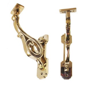 Puede incluir: Dos soportes de estante de latón ornamentados con un diseño de desplazamiento decorativo. Los soportes están diseñados para montarse en una pared y soportar un estante.