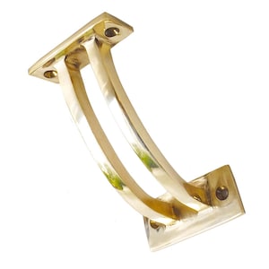 Puede incluir: Un soporte de latón pulido con un diseño curvo. El soporte tiene dos soportes curvos que conectan dos placas de montaje rectangulares. El latón tiene una superficie brillante y reflectante, y el diseño es simple y elegante.