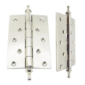 May include: Two polished nickel door hinges. Each hinge has a rectangular plate with rounded corners and multiple screw holes. The central barrel is composed of multiple sections. The top and bottom of each hinge have a decorative finial.