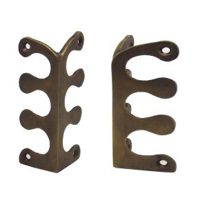 May include: Two antique brass-coloured corner braces. Each brace has a decorative, openwork design with three curved cutouts and three screw holes. The braces are designed to reinforce the corners of a wooden box or frame.