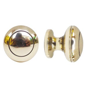 Könnte beinhalten: Zwei Türknöpfe aus Messing. Einer ist ein runder Knopf mit flacher Rückseite und kreisförmigem Design. Der andere ist ein zylindrischer Knopf mit abgerundeter Mitte und zwei ovalen Enden. Beide Knöpfe haben eine glänzende, reflektierende Oberfläche.