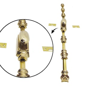 May include: A brass door bolt with an oval handle and decorative detailing. The bolt is long and slender, with several ornate rings and a rectangular base. Includes three small brass mounting plates.