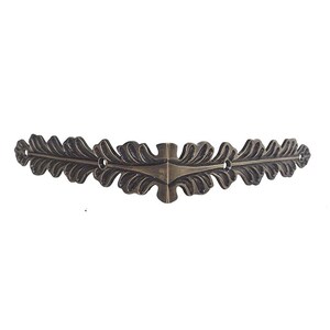 May include: A decorative metal corner bracket with a leaf design. The bracket is made of a dark, antique-looking metal and has a slightly curved shape.
