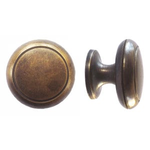 Könnte beinhalten: Zwei antike Messing-Schrankknöpfe. Einer ist rund mit einem kreisförmigen Design, der andere ist oval mit einem zylindrischen Schaft. Die Knöpfe haben ein Vintage-Aussehen.