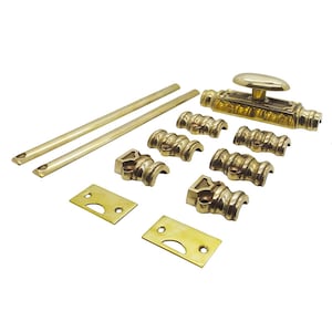May include: A collection of antique brass hardware components, including a door bolt with an oval handle, two long rods, several decorative brackets, and mounting plates. The hardware has a polished finish and is arranged on a white background.