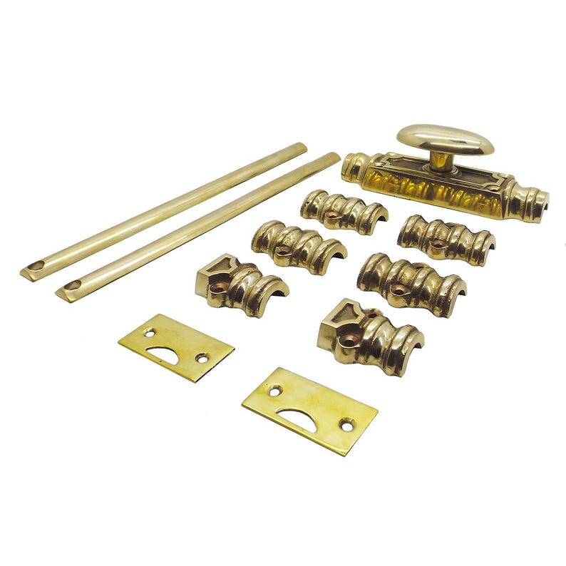 May include: A collection of antique brass hardware components, including a door bolt with an oval handle, two long rods, several decorative brackets, and mounting plates. The hardware has a polished finish and is arranged on a white background.