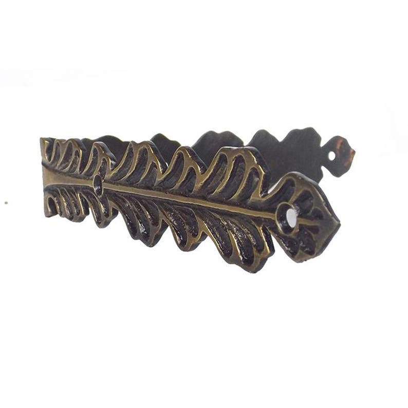 May include: A decorative metal bracket with a leaf design. The bracket is made of a dark metal with a gold finish. It has a detailed design with multiple leaves.