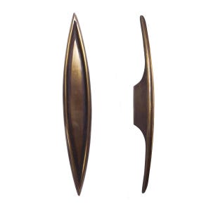 May include: Two antique brass cabinet door pulls, one is a long, narrow, oval shape and the other is a shorter, curved shape.