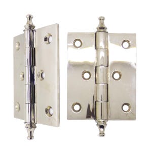 Puede incluir: Dos bisagras de puerta de níquel pulido. Cada bisagra tiene una placa rectangular con esquinas redondeadas y cuatro orificios para tornillos. El pasador central de la bisagra es cilíndrico con remates decorativos en la parte superior e inferior. Las bisagras están sobre fondo blanco.