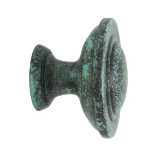May include: An aged cabinet knob with a dark teal and bronze finish. The knob has a rounded face with concentric rings and a cylindrical base. The hardware is designed for furniture and adds a vintage touch.