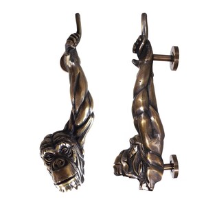 May include: A pair of ornate door handles shaped like a monkey's arm and hand. The handles are made of a dark bronze metal and have a detailed, realistic design.
