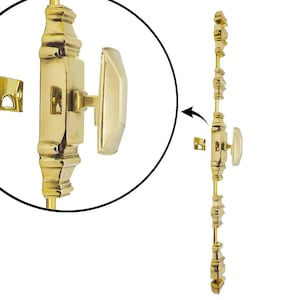 Może przedstawiać: Polerowana mosiężna blokada skrzydła okiennego o dekoracyjnym wzorze. Zamek posiada prostokątny korpus z dołączonym uchwytem i oddzielną płytką uderzeniową. Okucia przeznaczone są do bezpiecznego zamykania okien i dodają klasycznego akcentu.