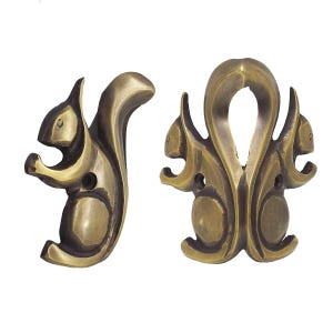 May include: Two antique brass squirrel-shaped cabinet pulls. One pull depicts a squirrel holding a nut, while the other features a symmetrical design with three squirrels. The pulls have a vintage, ornate style.