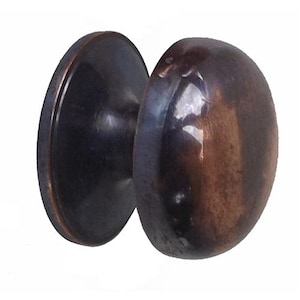 Może przedstawiać: Brązowa gałka do drzwi o owalnym kształcie i okrągłej płytce tylnej. Gałka ma błyszczącą, odblaskową powierzchnię i ciemne, metaliczne wykończenie, sugerujące styl vintage lub antyczny.