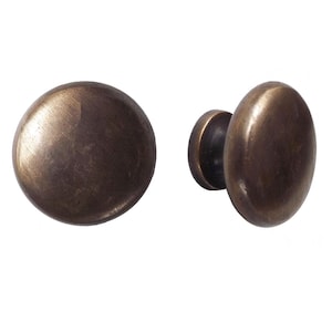 May include: Two antique bronze cabinet knobs. One knob is round, the other is oval. Both knobs have a dark, aged finish. These knobs are ideal for adding a vintage touch to furniture or cabinetry.
