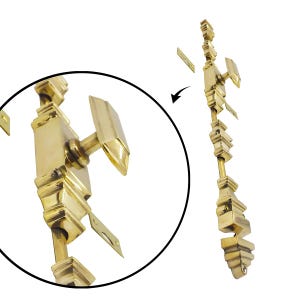 May include: A gold-colored door bolt with a decorative design. The bolt features a rectangular handle and a series of ornate, geometric shapes along its length. Includes mounting hardware.