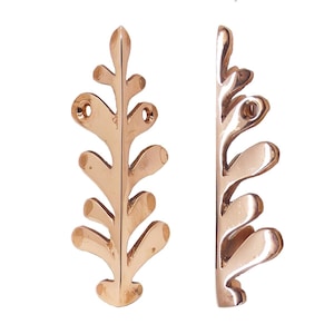 May include: Two bronze-coloured, leaf-shaped decorative metal pieces. Each piece has a stem-like base with several rounded, leaf-like protrusions. The pieces have holes for mounting. The design is symmetrical and elegant, suitable for home decor.