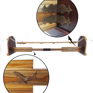 May include: Wooden bed frame with a whale-shaped metal accent. The frame has a light-colored wooden surface with dark brown accents. The headboard and footboard have a curved design. The frame is designed to hold a mattress.