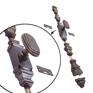 Puede incluir: Un pestillo de ventana de bronce antiguo con un asa ovalada y detalles decorativos. La cerradura incluye una serie de secciones rectangulares ornamentadas conectadas por una varilla y pequeñas placas metálicas para la instalación.