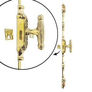 Puede incluir: Un juego de pestillo y manija de ventana de latón pulido. El juego incluye una barra larga y ornamentada con elementos decorativos, una manija con un diseño acanalado y una pequeña placa cuadrada. El hardware se muestra sobre un fondo blanco.