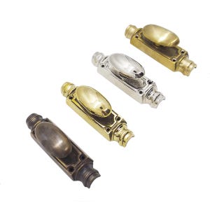 May include: Four metal cabinet pulls in various finishes: antique brass, polished brass, silver, and bronze. Each pull features an oval handle on a rectangular base with decorative detailing. Ideal for furniture restoration or new builds.