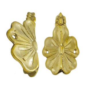 Puede incluir: Dos tiradores de armario con forma de flor, color latón. Cada tirador presenta un diseño floral detallado con un óvalo central y pétalos radiantes. Los tiradores tienen orificios para tornillos para el montaje.