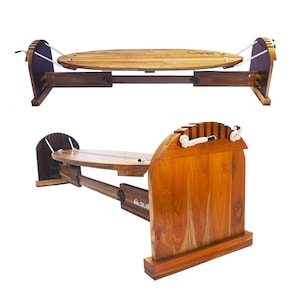 May include: A wooden surfboard rack with a light brown finish. The rack features a horizontal support structure with a curved top and a wooden surfboard. The rack is designed to hold a surfboard horizontally.